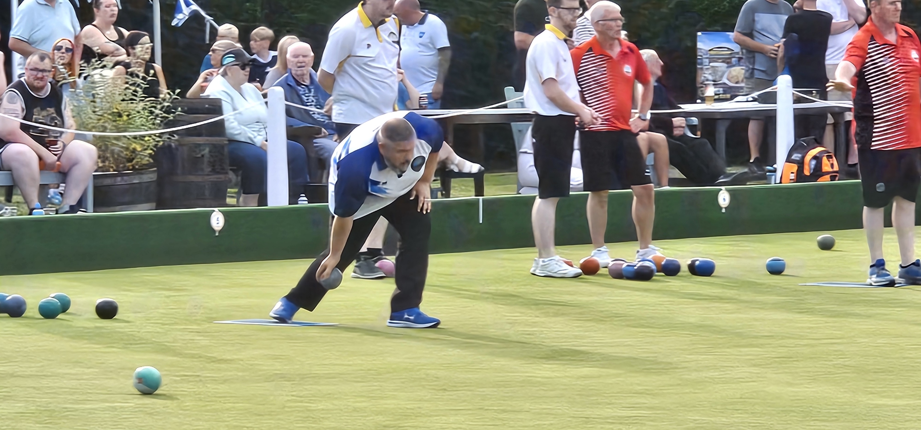 A dynamic shot of James "Basher" Brown in his Polmaise kit, fully focused on his delivery during the Gents Pairs final